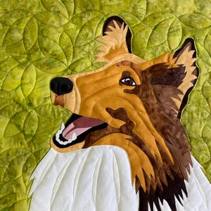 May include: A close-up of a brown and white dog's head with its mouth open, showing its teeth. The dog is against a green background with a quilted pattern.