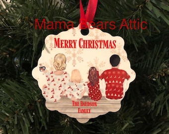 May include: A white ceramic Christmas ornament with a red ribbon. The ornament features a family of four in red and white pajamas with a snowflake pattern. The text "Merry Christmas" is at the top of the ornament and "The Baudson Family" is at the bottom.