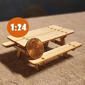 May include: A miniature wooden picnic table, 1:24 scale, with a penny for size comparison. The table is made of light brown wood and has a simple design.