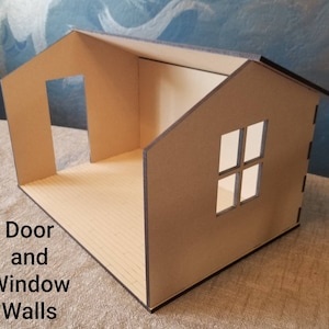 May include: A cardboard model of a small house with a door and window opening. The house is made of brown cardboard and has a simple design. The roof is flat and the walls are straight. The house is sitting on a light brown surface.