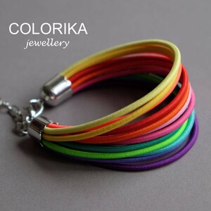 May include: A rainbow coloured bracelet made of multiple strands of elastic cord. The bracelet has a silver clasp.