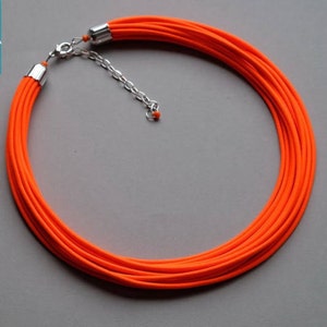May include: A bright orange multi-strand necklace with a silver clasp and chain.