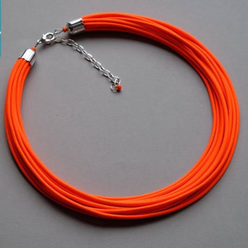 May include: A bright orange multi-strand necklace with a silver clasp and chain.