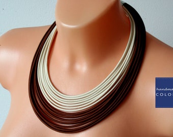 May include: A multi-layered necklace with brown and white bands. The necklace is handmade by Colorika.