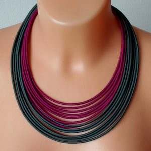 Könnte beinhalten: Eine mehrlagige Halskette mit abwechselnden dunkelgrünen und burgunderfarbenen Stoffbändern.