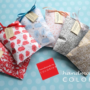 May include: Five small gift bags with different floral patterns and ribbons. Each bag has a tag that says "handmade by COLORIKA".