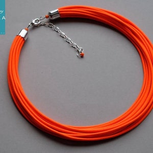 May include: A bright orange multi-strand necklace with a silver clasp.