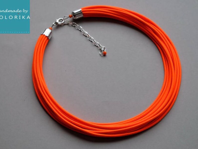 May include: A bright orange multi-strand necklace with a silver clasp.