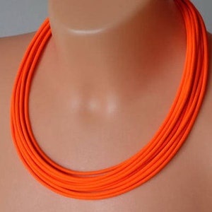 May include: A bright orange multi-strand necklace made of fabric. The necklace is layered and creates a bold statement.