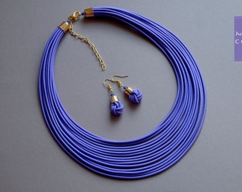 May include: A purple multi-strand necklace with a gold clasp and matching purple earrings with gold accents.