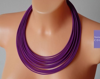 May include: A purple multi-strand necklace made of fabric. The necklace is layered and creates a thick, chunky look.