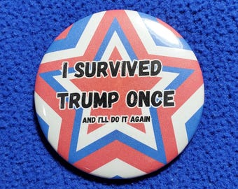 May include: A round button with a red, white, and blue starburst design. The text "I SURVIVED TRUMP ONCE AND I'LL DO IT AGAIN" is printed in white on the button. The button is set against a blue textured background.
