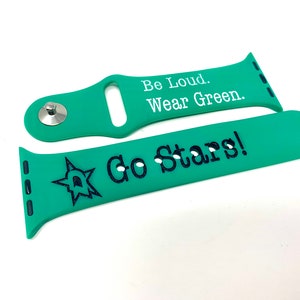 May include: A green Apple Watch band with white text that reads "Be Loud. Wear Green." and a second band with black text that reads "Go Stars!" and a black star graphic.