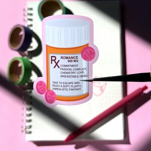 The image shows a sticker shaped like an orange and white medical pill bottle. The bottle is for the romance genre in books, movies, television, and other forms of media. The design is accented with pink and pills with hearts on it. The text reads- Romance 888mg. 
Commitment, passion, conflict, chemistry, love, irresistible hero.
Take to escape and enjoy a soft fluffy, unrealistic fantasy.