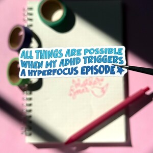 May include: A white sticker with blue text that reads "All things are possible when my ADHD triggers a hyperfocus episode" with a blue star to the right of the text.