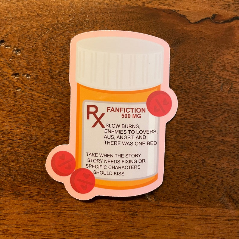 The image shows a sticker shaped like an orange and white medical pill bottle. The bottle is for the fantiction genre in books, movies, television, and other forms of media. The design is accented with red and pills with hearts on it. The text reads- Fanfiction 500mg. 
Slow burns, enemies to lovers, AUs, angst, and there was one bed. 
Take when the story needs fixing or specific characters should kiss.