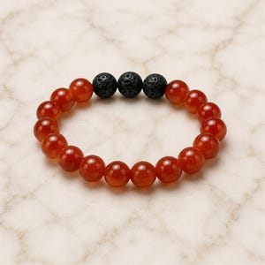May include: A beaded bracelet featuring smooth, round, translucent orange-red carnelian beads arranged in a circular band, accented by three textured, porous, matte black lava stone beads positioned together at the top of the circular arrangement.