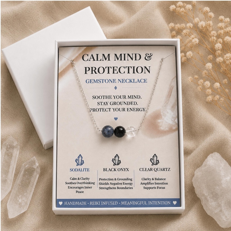 May include: A silver-toned chain necklace featuring three beads: a blue sodalite, a black onyx, and a clear quartz. The necklace is displayed on a white card with the text CALM MIND & PROTECTION GEMSTONE NECKLACE and descriptions of each stone.