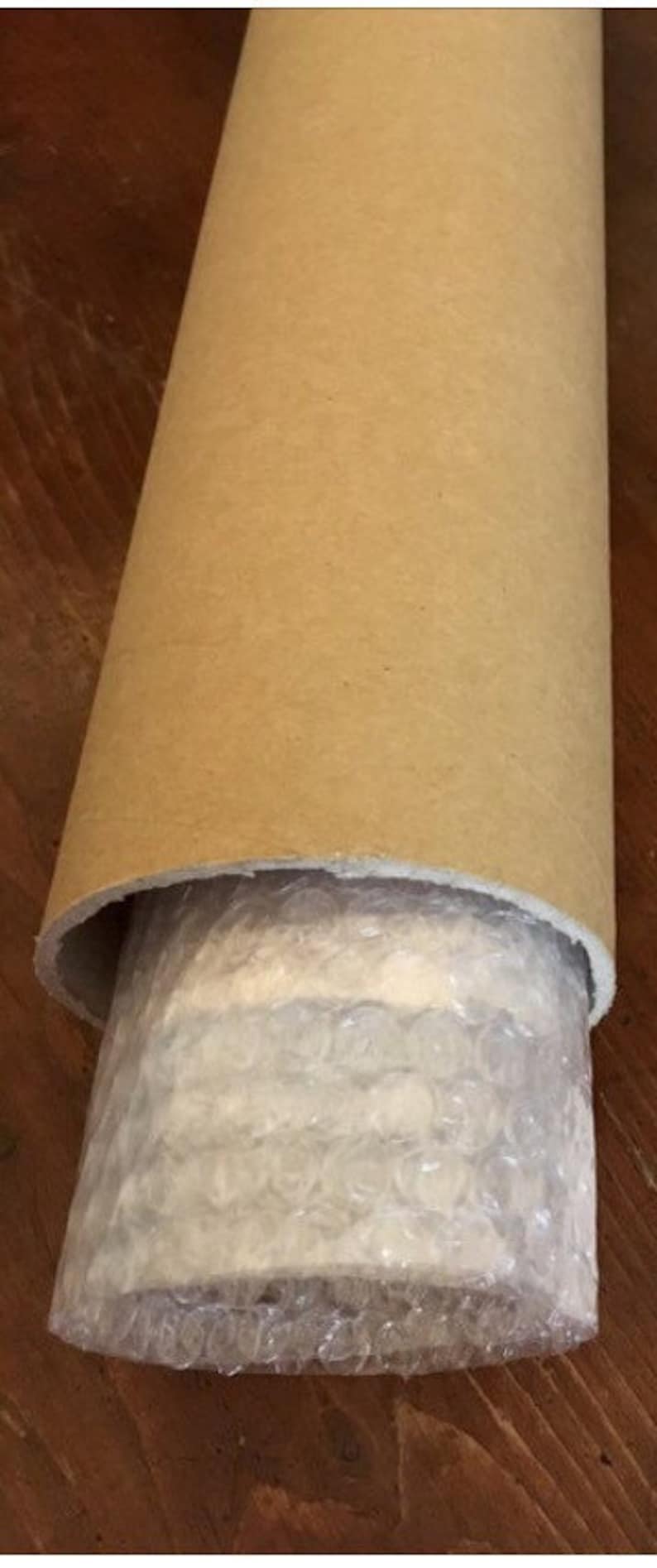 Puede incluir: Un tubo de cart&oacute;n marr&oacute;n con un forro de pl&aacute;stico de burbujas blanco en el interior. El tubo est&aacute; enrollado y el pl&aacute;stico de burbujas es visible.