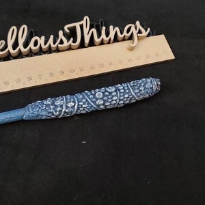 May include: A blue and white wand with a textured design. The wand is approximately 30 cm long.