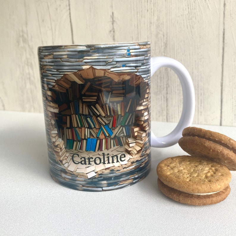 May include: White ceramic mug with a colorful image of a wall of books with a hole in the middle. The name "Caroline" is printed on the mug.