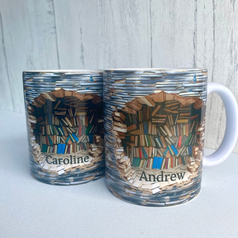 May include: Two white ceramic mugs with a colorful image of a bookshelf filled with books. The mugs have the names "Caroline" and "Andrew" printed on them.