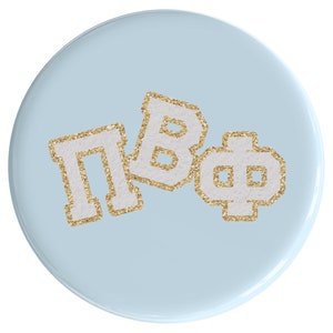 May include: A light blue round button with the letters "ПВΦ" in white with gold glitter.