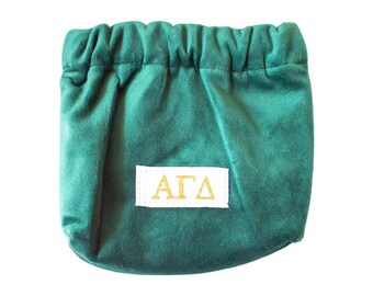 May include: A green velvet drawstring bag with a white label that says "AGD" in gold lettering.