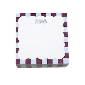 May include: A stack of square notepads with a white scalloped border and a maroon and white checkered pattern. The top notepad has the letters "ПВФ" in blue. The center of the notepad is white.