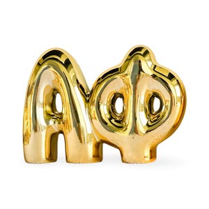 May include: Gold-colored ceramic sculpture of the letters "A" and "Phi" in a balloon-like style.
