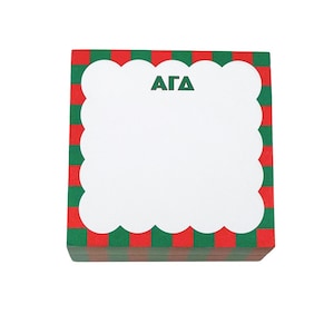 May include: A stack of square notepads with a red and green checkered border. The top of the notepad has a white, scalloped edge with the letters "ΑΓΔ" in green. The notepad is likely for taking notes or writing messages.