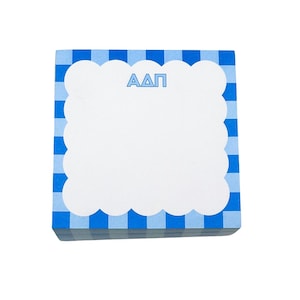 May include: A stack of square notepads with a blue and white gingham border. The notepad has a white scalloped edge and the Greek letters ΑΔΠ in blue at the top.