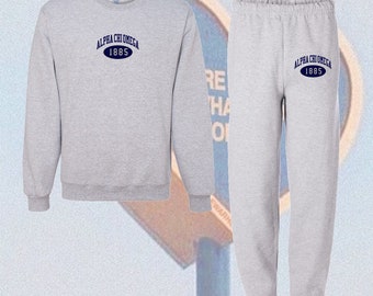 May include: Gray sweatshirt and sweatpants set with the text "Alpha Chi Omega 1885" in blue on the front of each piece.