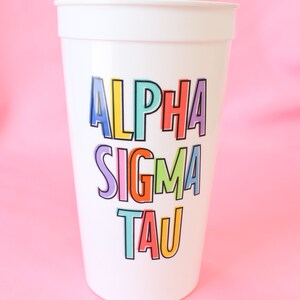 May include: White plastic cup with the words "Alpha Sigma Tau" in colorful letters.