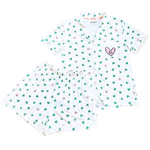 May include: White pajama set with a green and pink heart pattern. The short-sleeved top has a breast pocket with a pink heart and the letters "AL". The shorts have an elastic waistband.
