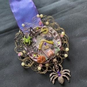 The Halloween Spider Altered Tin is made from a repurposed tin. upcycled jewelry, clay haunted house and pumpkin, metal lace, and gems.