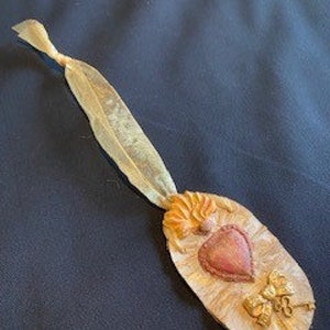 Altered Tin made from vintage tin pan, smashed, painted, sanded & embellished with molded clay heart and flame.