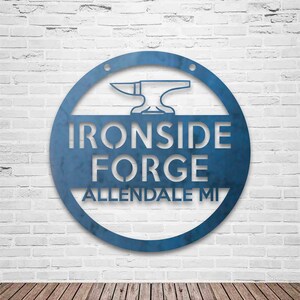 May include: A blue metal circular sign featuring a white silhouette of an anvil and the text "Ironside Forge Allendale MI".
