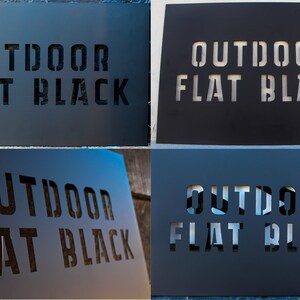 Op de afbeelding: Vier metalen borden met de tekst "OUTDOOR FLAT BLACK" uitgesneden in een sjabloonstijl. De borden zijn geschilderd in verschillende tinten blauw en grijs.