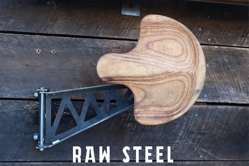 May include: A wooden wall-mounted stool with a unique curved seat and a black metal bracket. The bracket is attached to the wall with screws and has a triangular design. The text "RAW STEEL" is printed on the wall below the stool.