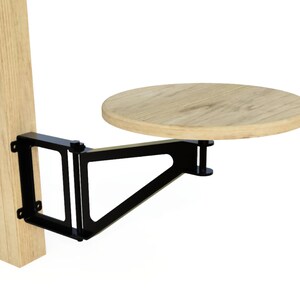 May include: A black metal folding table bracket attached to a wooden post, supporting a round wooden table top.