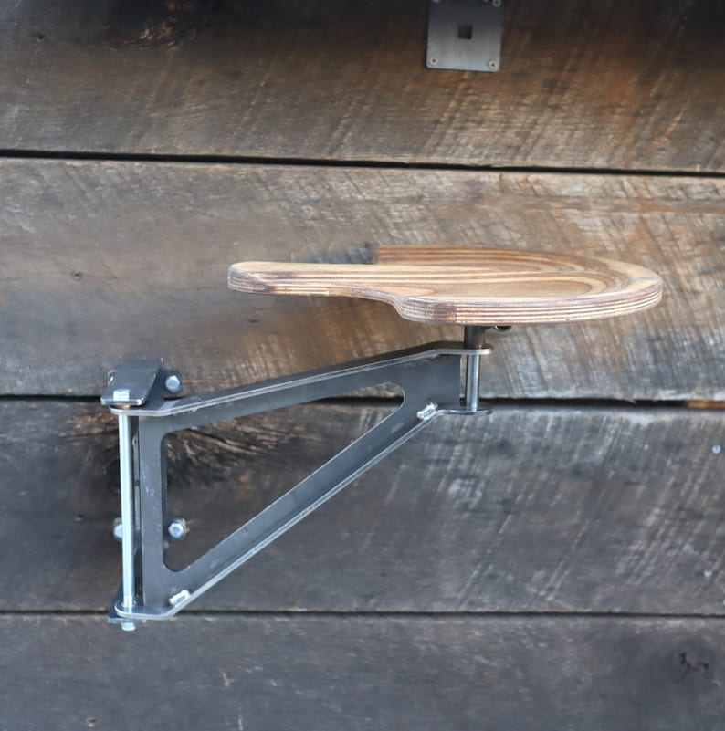 May include: A wooden shelf with a metal bracket attached to a wooden wall. The shelf is curved and has a natural wood finish. The bracket is black and has a triangular shape.