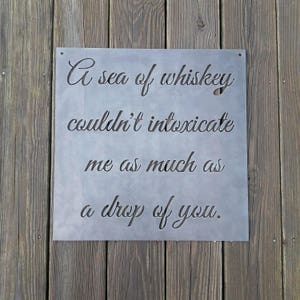 May include: A metal sign with the text "A sea of whiskey couldn't intoxicate me as much as a drop of you."