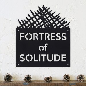 May include: Black metal sign with a white silhouette of a fortress and the text "Fortress of Solitude".