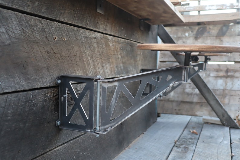 Puede incluir: Una barra de metal con un dise&ntilde;o triangular est&aacute; montada en una pared de madera. La barra sostiene un taburete de bar de madera con un mecanismo giratorio de metal.