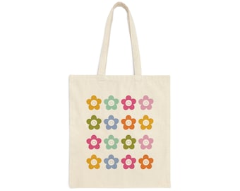 Peut inclure: Sac fourre-tout crème avec un motif répété de fleurs souriantes colorées. Les fleurs sont jaunes, vertes, bleues, roses et oranges. Le sac a deux poignées pour le transport.