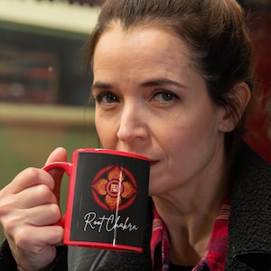 May include: A red ceramic mug with a black handle and a black design featuring a red and gold mandala with the text "Root Chakra".