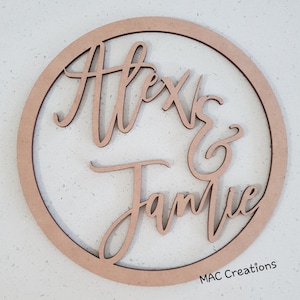 May include: A wooden circle with the names "Alexis & Jamie" written in cursive script. The circle is unfinished and has a natural wood color. The text "MAC Creations" is visible in the bottom right corner.