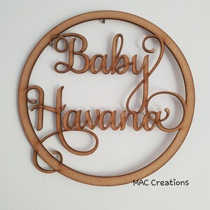 May include: A wooden circle with the words "Baby Havanna" written in a decorative script font.