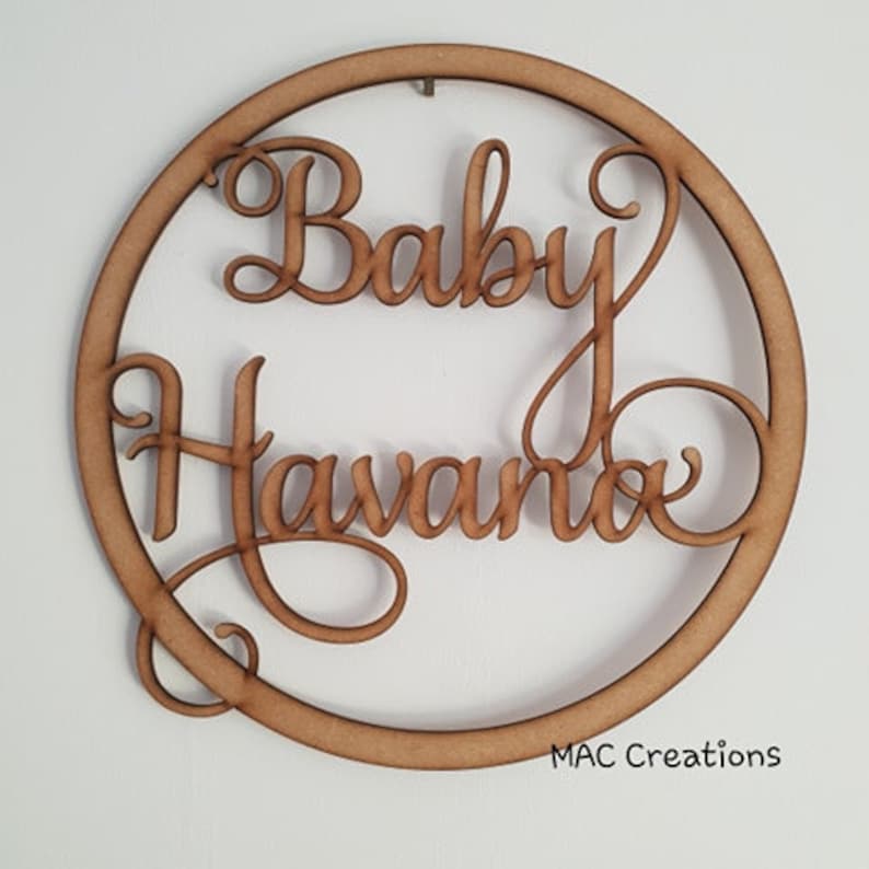 May include: A wooden circle with the words "Baby Havanna" written in a decorative script font.